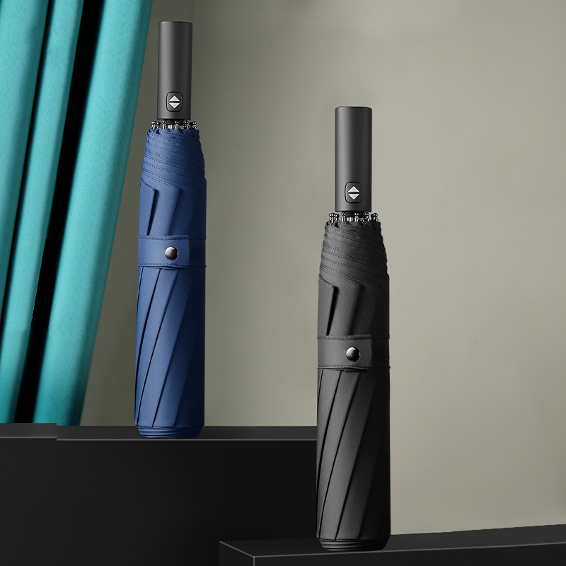 Custom automatic compact folding umbrellas, showcasing premium navy and black business options on a stepped display for corporate gift wholesale by the manufacturer.