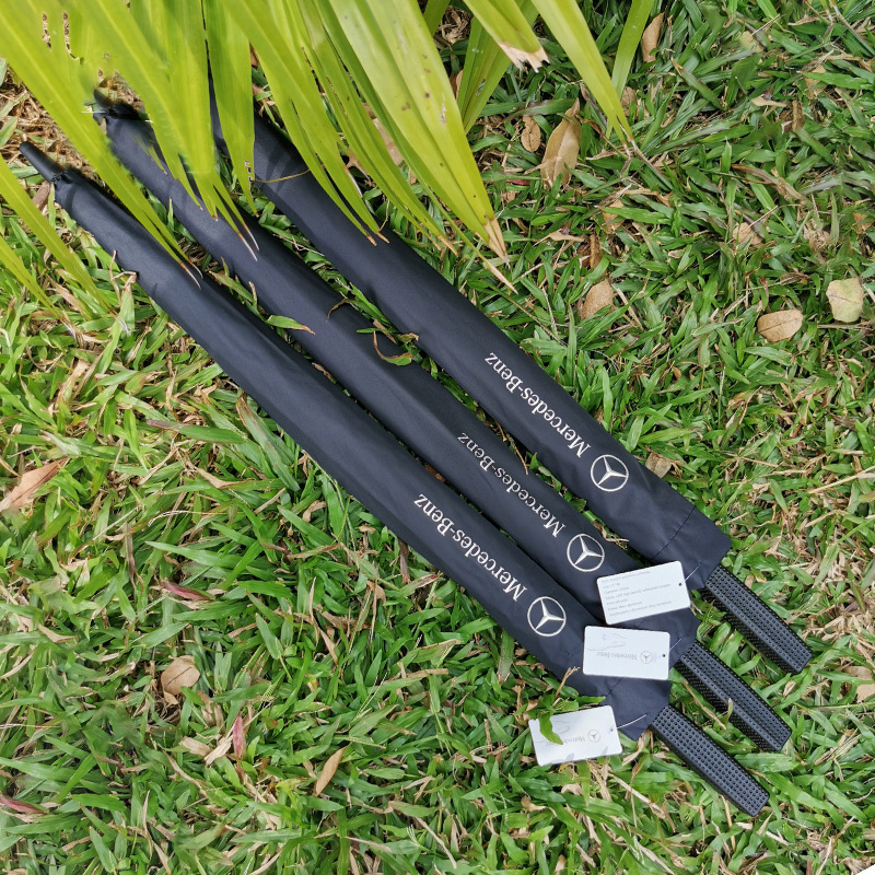 Custom branded Mercedes-Benz promotional golf umbrellas, showcasing white logo printing on black premium sleeves and textured handles for automotive dealership gifts wholesale by the manufacturer.