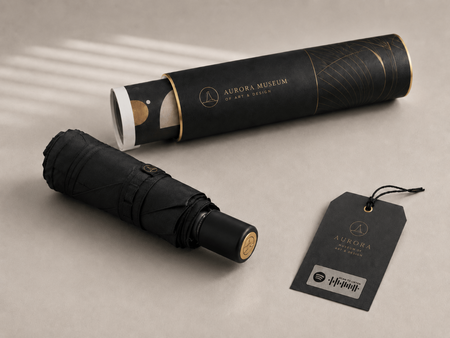 Custom corporate gift umbrellas with matching luxury packaging for art galleries and luxury institutions, showcasing full-bleed matte black printing, gold foil stamped paper canisters, and interactive scannable retail hangtags provided by the manufacturer for volume promotional wholesale.