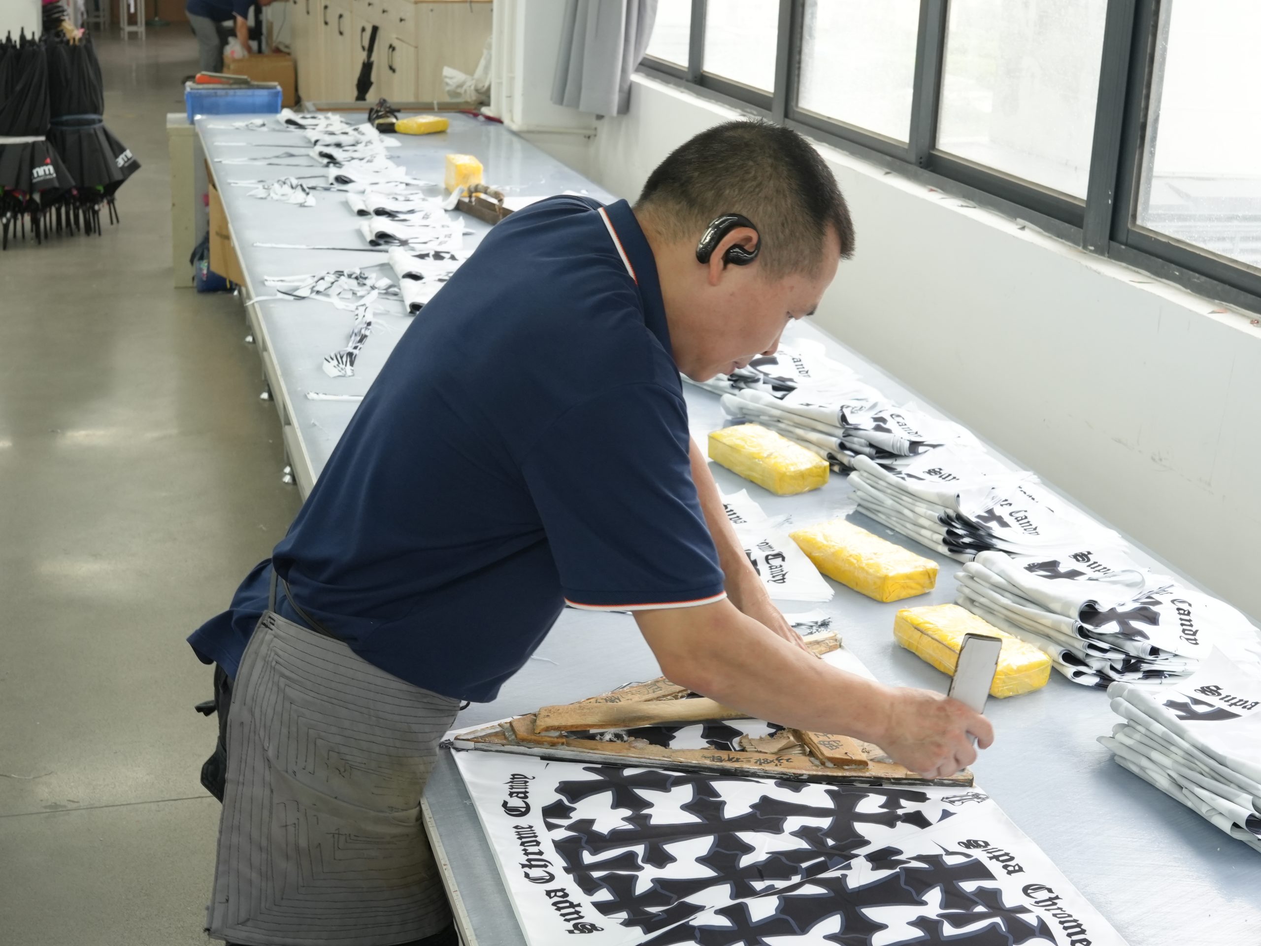 Inside our BSCI-certified umbrella factory: a technician precisely cutting high-quality canopy fabric for a bulk custom umbrella order, showcasing our direct manufacturing capabilities, strict quality control, and efficient OEM production lines.